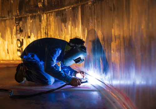 Welding  arc argon worker male repaired metal is welding sparks industrial construction tank stainless oil inside confined spaces.